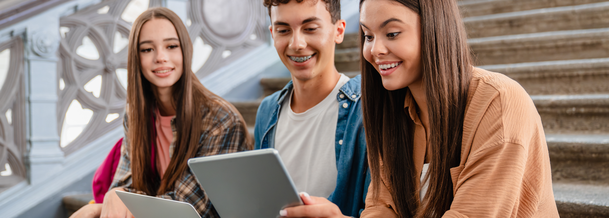 Scholieren zitten bij elkaar op een trap en bekijken een leuk bericht op laptop